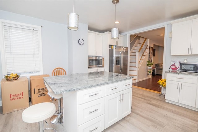 kitchen featuring white cabinets, appliances with stainless steel finishes, and pendant lighting