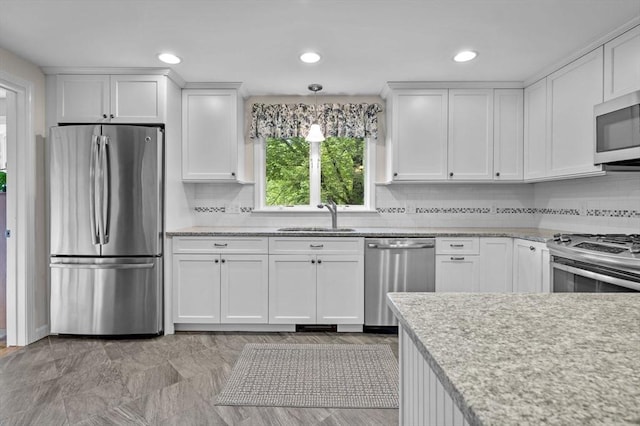 kitchen with appliances with stainless steel finishes, white cabinets, and a sink