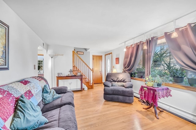 living room with light hardwood / wood-style floors, baseboard heating, and a wealth of natural light