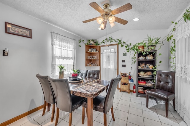 dining room featuring ceiling fan, lofted ceiling, a textured ceiling, and light tile patterned floors