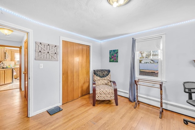 sitting room featuring baseboard heating and light hardwood / wood-style floors