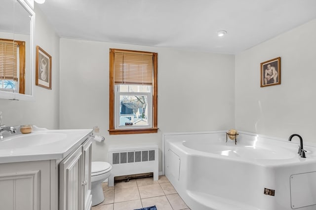 bathroom with vanity, radiator, tile patterned floors, toilet, and a tub to relax in