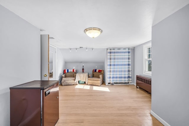 living area with radiator heating unit, light wood-type flooring, and rail lighting