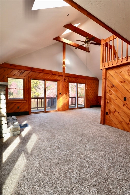 unfurnished living room with wooden walls, a skylight, and plenty of natural light