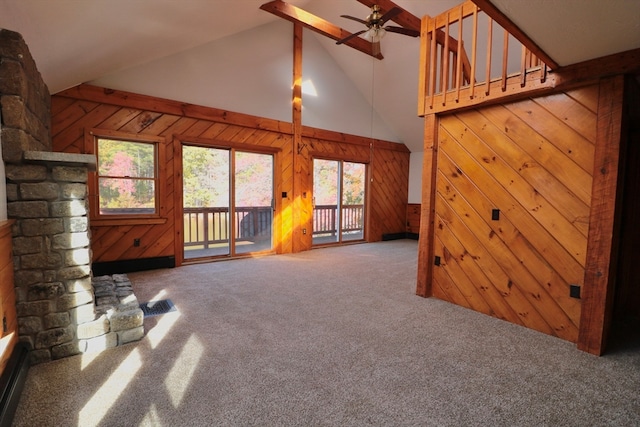 unfurnished living room with carpet floors, beam ceiling, wooden walls, and high vaulted ceiling