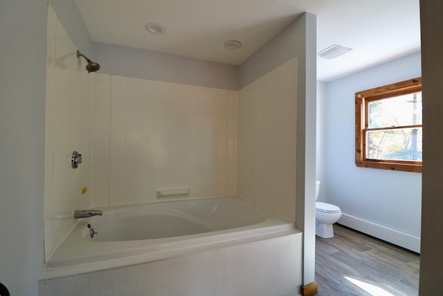 bathroom with toilet, shower / washtub combination, baseboard heating, and hardwood / wood-style flooring