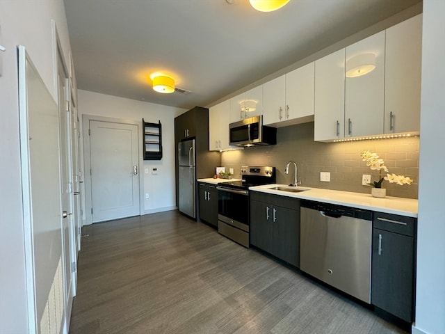 kitchen with dark hardwood / wood-style flooring, stainless steel appliances, backsplash, white cabinetry, and sink