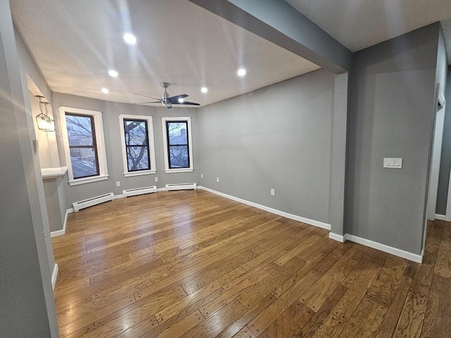 empty room featuring hardwood / wood-style flooring and baseboard heating