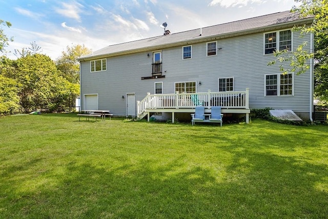 rear view of house featuring a wooden deck, a yard, and a garage