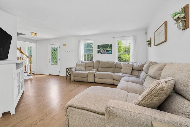 living room with light wood-style flooring, stairs, and baseboards
