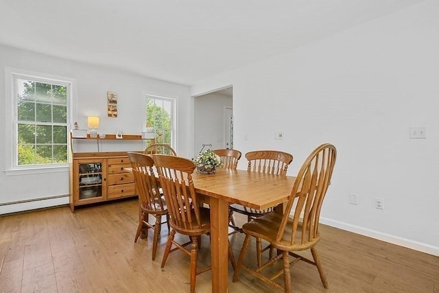 dining room with light wood-type flooring, a baseboard heating unit, and baseboards