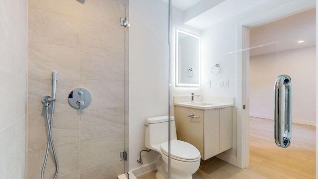 full bath with a tile shower, vanity, toilet, and wood finished floors