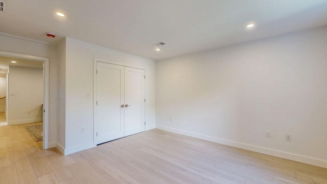 unfurnished bedroom featuring light wood finished floors, baseboards, recessed lighting, and a closet