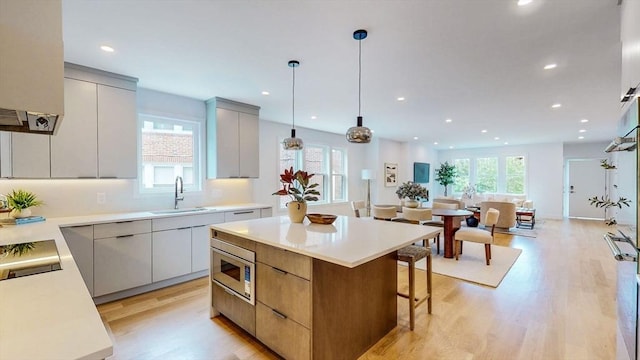 kitchen featuring a sink, stainless steel microwave, modern cabinets, a kitchen island, and recessed lighting