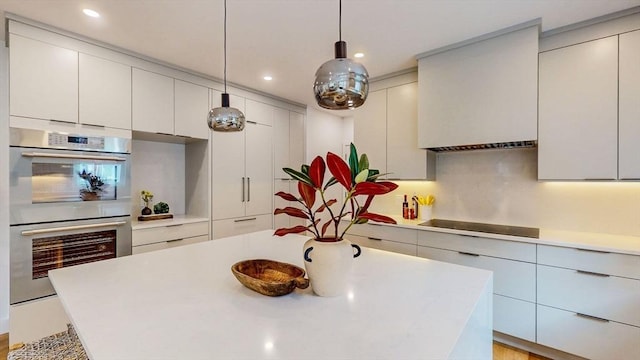 kitchen with double oven, light countertops, black electric cooktop, a kitchen island, and recessed lighting