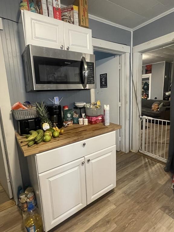 bar with hardwood / wood-style flooring, crown molding, butcher block counters, and white cabinets