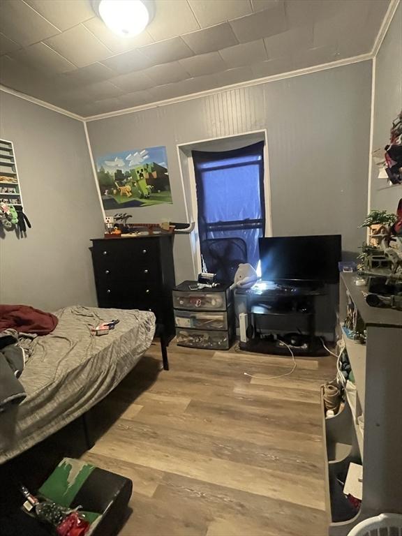 bedroom with ornamental molding and hardwood / wood-style floors