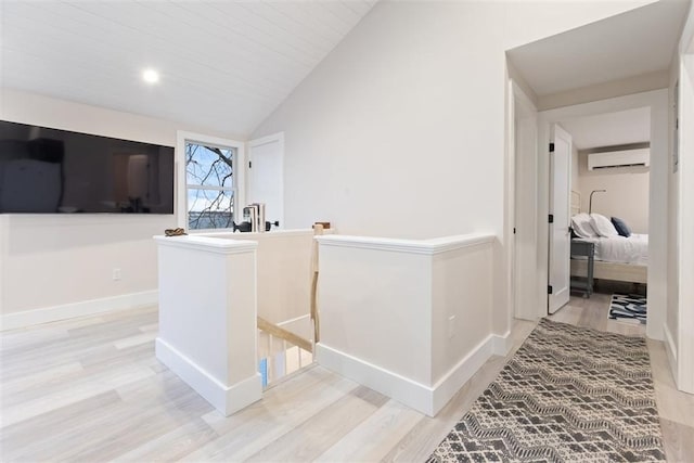 69 Naugus Ave, Marblehead, MA 01945 - corridor with an upstairs landing, light wood-type flooring, vaulted ceiling, a wall unit AC, and baseboards