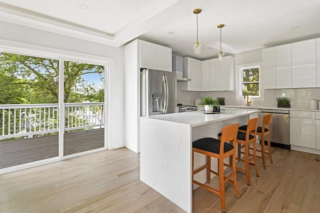 96 Dutton St, Malden, MA 02148 - kitchen featuring stainless steel appliances, backsplash, a kitchen bar, light wood-style flooring, and white cabinets
