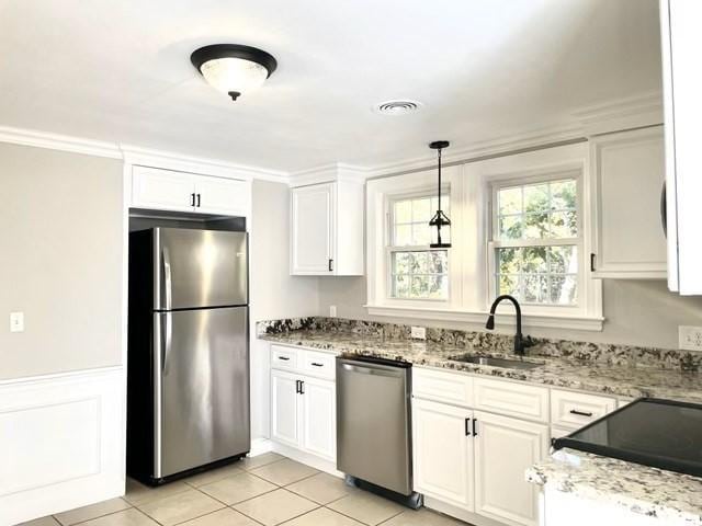 kitchen with white cabinetry, stainless steel appliances, sink, hanging light fixtures, and light tile patterned floors