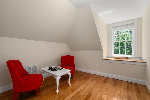 living area featuring light wood finished floors, baseboards, and lofted ceiling
