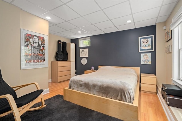 bedroom with wood finished floors, a paneled ceiling, recessed lighting, and baseboards