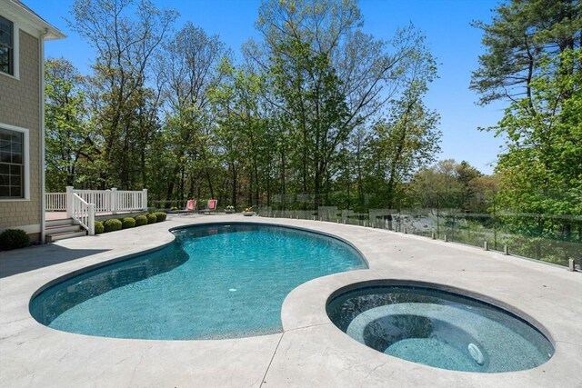 swimming pool with an in-ground hot tub, a wooden deck, a patio area, and fence