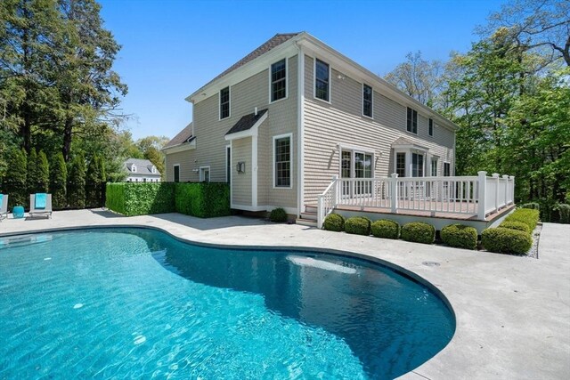 outdoor pool with a wooden deck and a patio