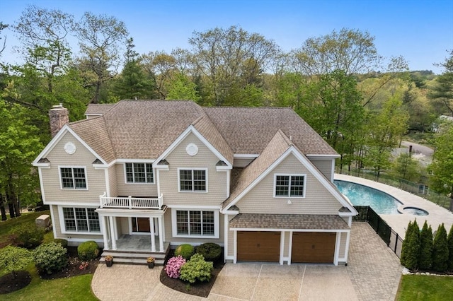 view of front of home with driveway, a shingled roof, a chimney, and an attached garage