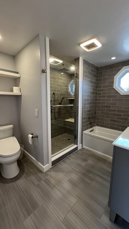 628 Malden St, Revere, MA 02151 - bathroom with toilet, a garden tub, a shower stall, baseboards, and vanity