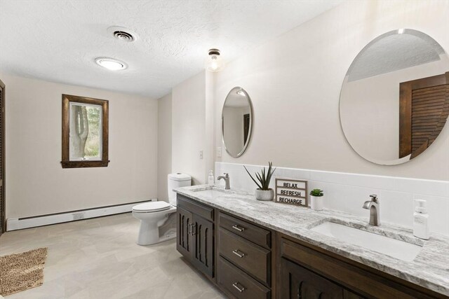 126 Prospect Hill St, Taunton, MA 02780 - bathroom featuring a baseboard heating unit, double vanity, toilet, and a textured ceiling