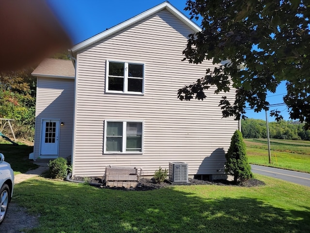 view of side of property with a lawn and central AC