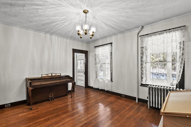 foyer entrance with radiator, dark hardwood / wood-style flooring, a notable chandelier, a textured ceiling, and ornamental molding