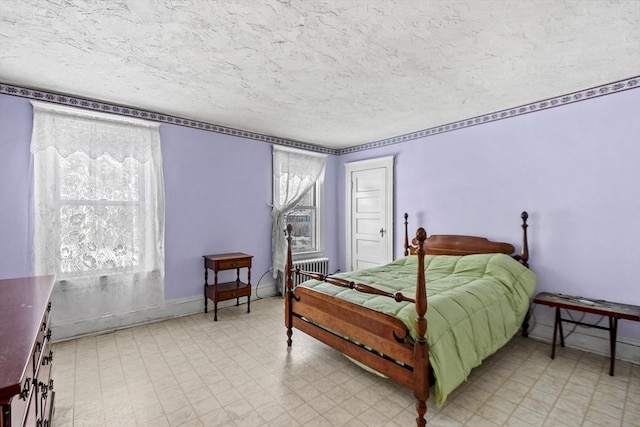 bedroom featuring radiator heating unit, a textured ceiling, and multiple windows