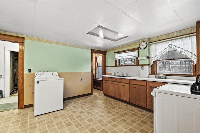 kitchen with stove, sink, washer / clothes dryer, and tile walls