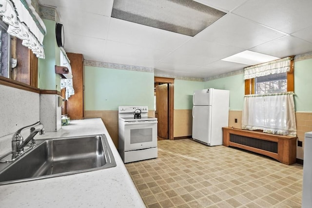 kitchen with a paneled ceiling, white appliances, and sink