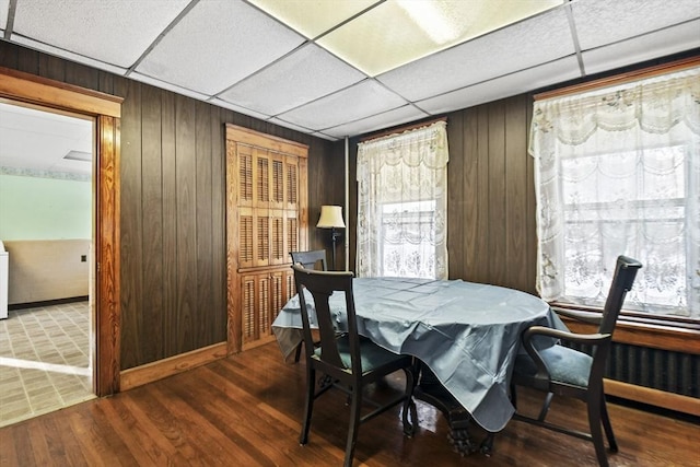 dining room with washer / clothes dryer, wooden walls, hardwood / wood-style floors, and a drop ceiling