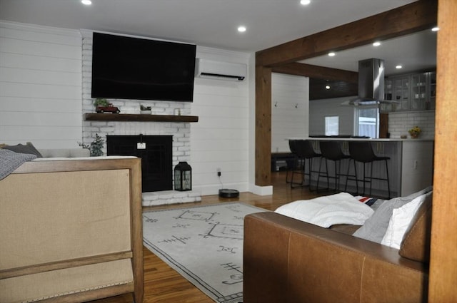 living room with hardwood / wood-style floors, a wall mounted air conditioner, a fireplace, beamed ceiling, and wood walls