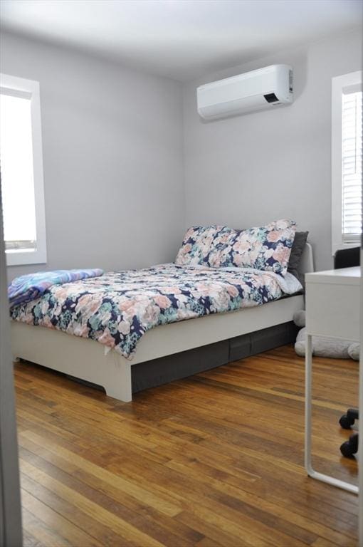 bedroom featuring hardwood / wood-style floors and a wall unit AC