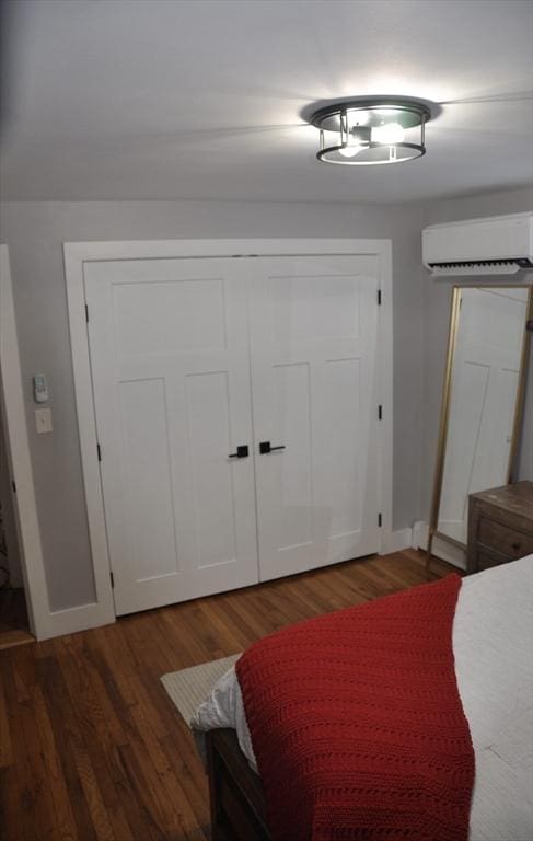 bedroom featuring a closet, dark hardwood / wood-style floors, and an AC wall unit