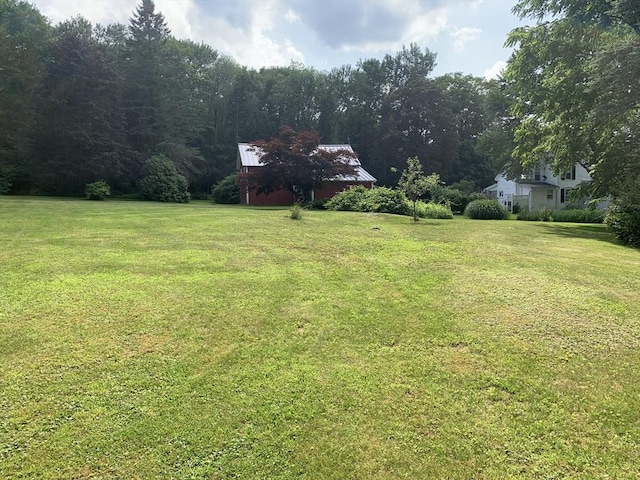 293 Washington, Warren, MA 01083 - view of grassy yard featuring a wooded view and a barn
