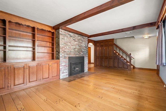 4 Farmland Rd, Saugus, MA 01906 - unfurnished living room with light wood-style flooring, beamed ceiling, a fireplace, stairway, and baseboards