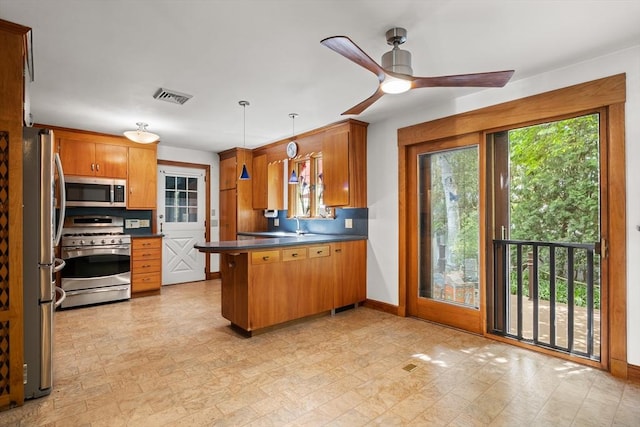 4 Farmland Rd, Saugus, MA 01906 - kitchen featuring appliances with stainless steel finishes, a peninsula, ceiling fan, dark countertops, and brown cabinetry