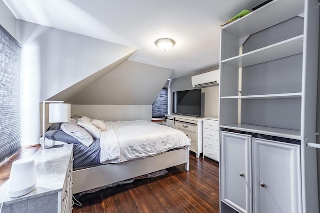 bedroom with lofted ceiling, a wall unit AC, and dark hardwood / wood-style floors