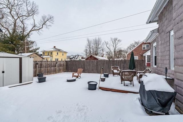 snowy yard with a fire pit and a shed