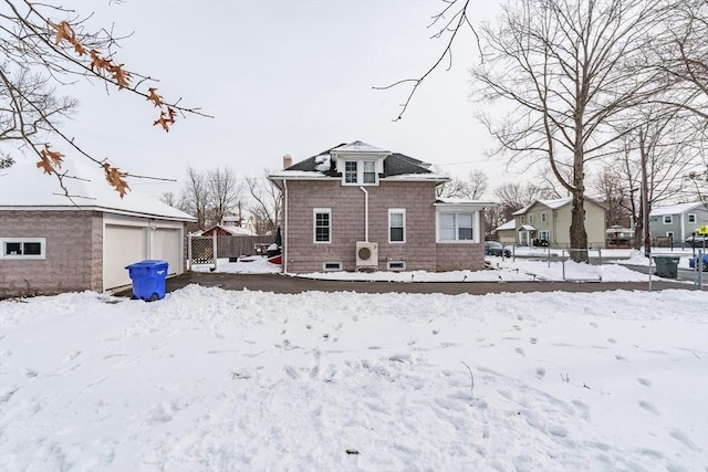 snow covered property with a garage, an outdoor structure, and ac unit