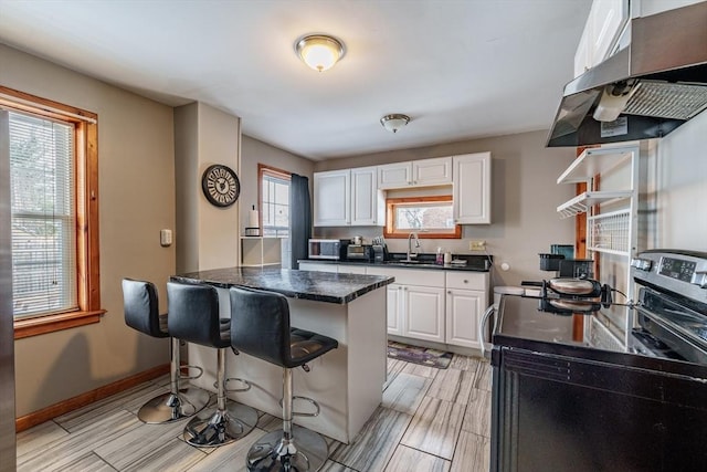 kitchen with stainless steel electric stove, sink, a breakfast bar area, white cabinets, and exhaust hood