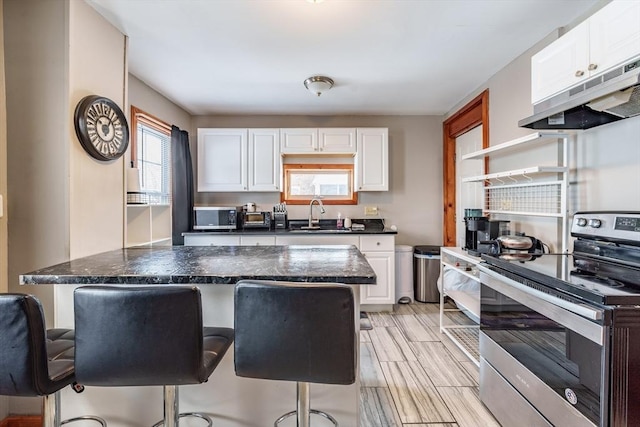 kitchen featuring stainless steel appliances, a kitchen bar, sink, and white cabinets