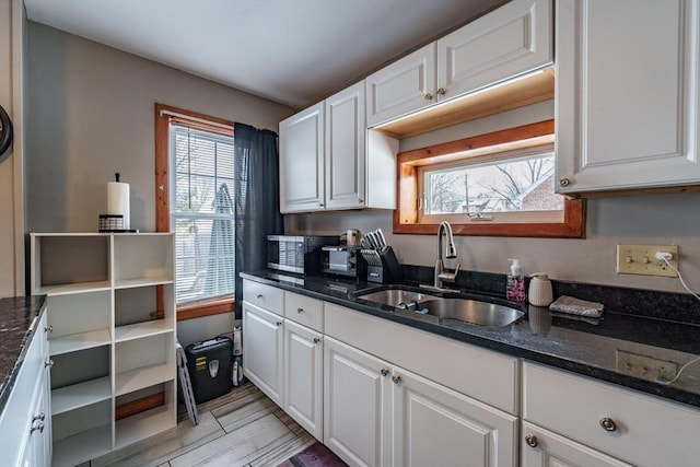 kitchen with dark stone countertops, sink, and white cabinets