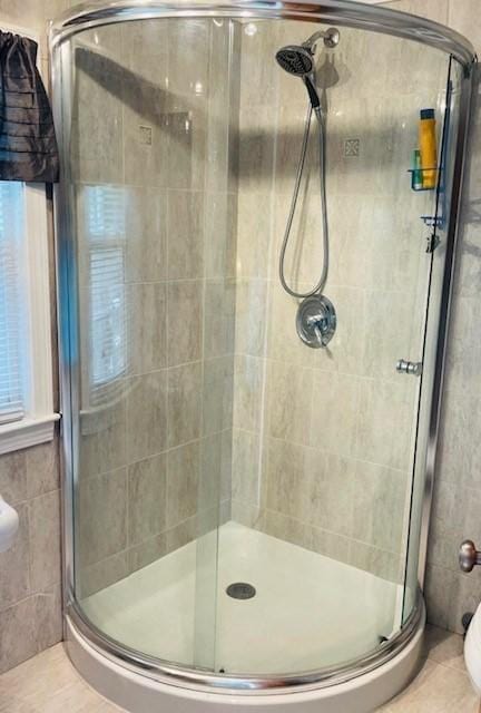 bathroom with tile patterned flooring, a shower with shower door, and tile walls